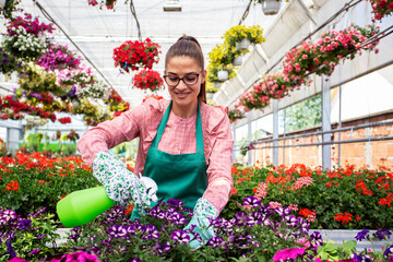 Woman in botanical garden work with flowers and spray with water