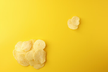 Crispy potato chips snacks on yellow background. Image top view, flat lay, and copy space.