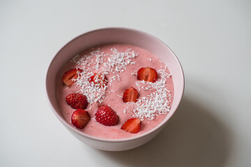 Delicious smoothie bowl in pink bowl on a white table