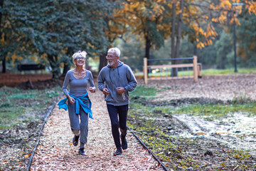 Fototapeta premium Aged couple jogging in the public park and smile