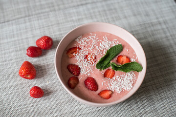 Delicious smoothie bowl in pink bowl on a grey table