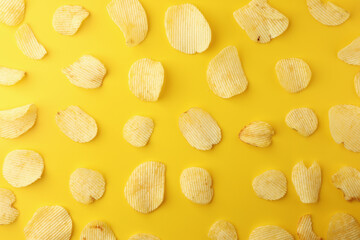 Crispy potato chips snacks on yellow background. Image top view, flat lay.