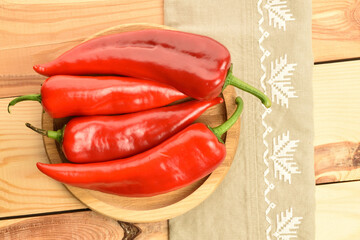 Red sweet organic peppers, close-up, on a wooden table.