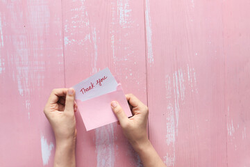 women's hand holding thank you letter , top down 