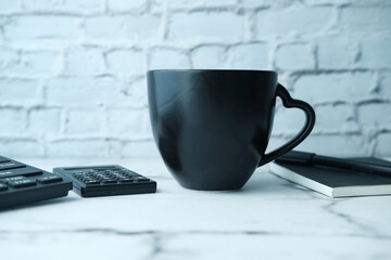 Black mug mockup with with keyboard, notebooks on table 