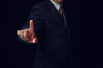 Businessman wearing a black suit, touch with an index finger. Concept, business, industrial, success on black background.