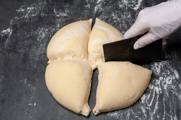 Dividing homemade dough for a Pizza. Surrounded by flour on a slate plate.