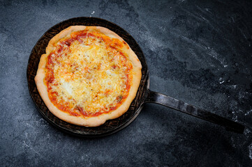 Fresh Pizza in an rustic iron Pan on a Slate Plate
