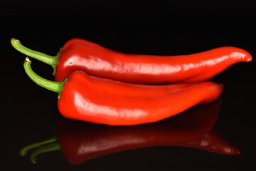 Red organic bell peppers, close-up, on a black background.