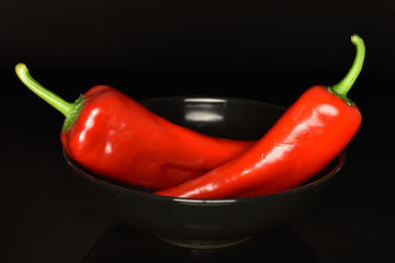 Red organic bell peppers, close-up, on a black background.