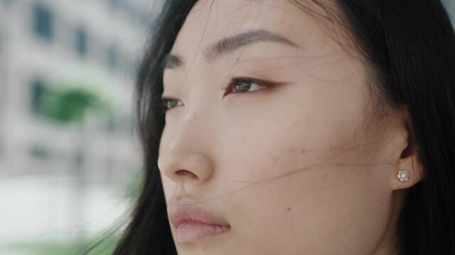 Close up face young asian woman portrait looking away serious confident beautiful young urban casual natural city pretty slow motion