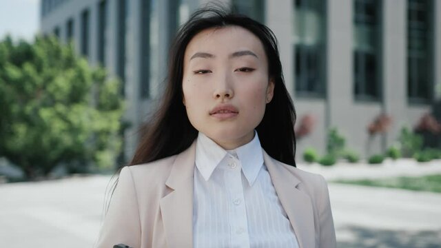 Successful young asian woman portrait look at camera stand on street confident beautiful urban casual natural city pretty slow motion