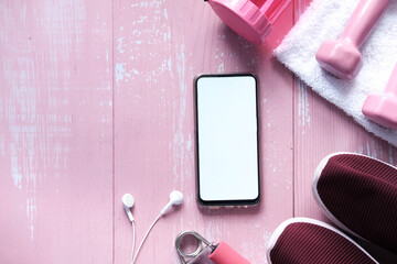 Smart phone with sports equipment on wooden floor.