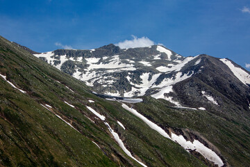 Fototapeta na wymiar Snowy mountains that begin to melt and become green with spring and around