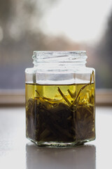 Chives Oil in Glass Jar in front a window