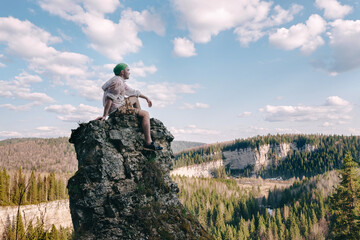 Young hiker sitting and relaxing on top of a mountain