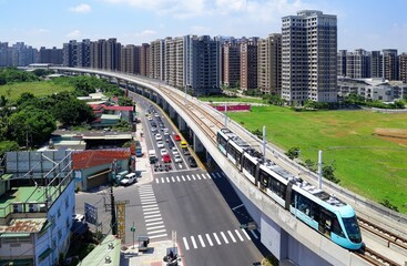 Aerial view of metro trains passing each other on a curve  near Xinshi 1st Road Station next to residential towers in a community in Tamsui District, New Taipei City