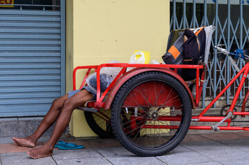 Obraz na płótnie Canvas Sleeping homeless on old rickshaw in Bangkok