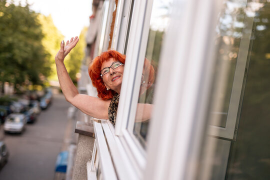 Elderly woman waving through the window