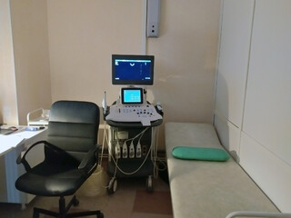 Medical diagnostic equipment, a couch for examination and a black doctor's chair. Ultrasonic diagnostic device. The monitor is blue. Diagnostics. The doctor's office. Medical topic.