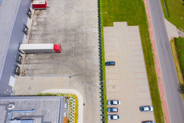 Aerial view of goods warehouse. Logistics center in industrial city zone from above. Aerial view of trucks loading at logistic center. View from drone.