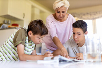 Obraz premium Mother helping her kids doing homework at home 