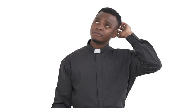 Portrait of forgetful black priest scratching the back of his head trying to remember something and it doesn't work out for him isolated on white background.