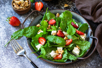 Healthy food concept, Diet salad plate. Summer salad with strawberries, fetacheese and walnut on a stone countertop.