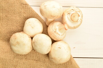 Freshly cut mushrooms, close-up, on jute fabric on a white wooden table.