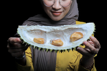 Asian woman holding durian skin containing durian seeds