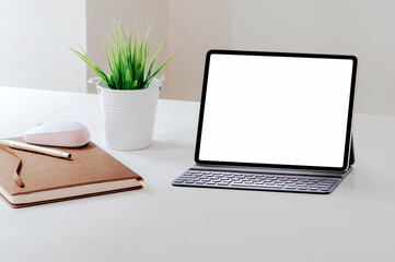 Mockup blank screen tablet with keyboard on white top table.