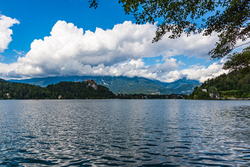Big lake with green mountains on the background under white clouds