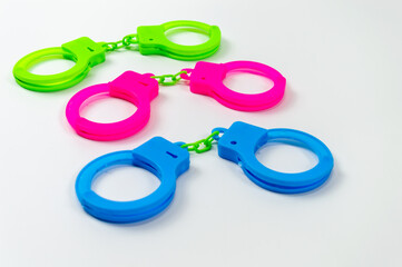 The toy handcuffs are available in green, pink and blue. On a white background.