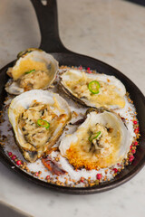 Oysters Rockefeller. Oysters topped with cheese, cream, garlic onions oven baked and garnished with fresh diced jalapeños. Classic American restaurant or French bistro appetizer.