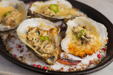 Oysters Rockefeller. Oysters topped with cheese, cream, garlic onions oven baked and garnished with fresh diced jalapeños. Classic American restaurant or French bistro appetizer.