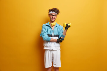 Its too hard for me. Determined man lifts dumbbells with intense expression, goes in for sport at...