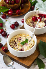 Homemade summer dessert. Cherry crumble in baking dish on a wooden tabletop.