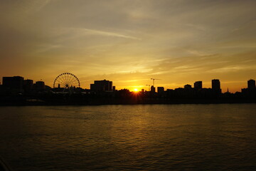 Obraz premium A skyline of Montreal Old Port and Downtown at sunset. Foreground is Saint Laurent river