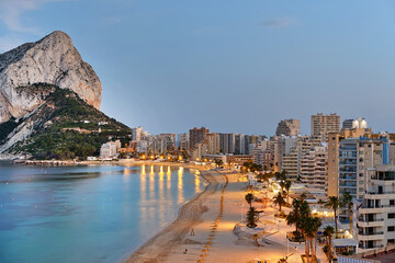 Panoramic view from above of Calpe cityscape. Street lights illuminating seafront promenade during...