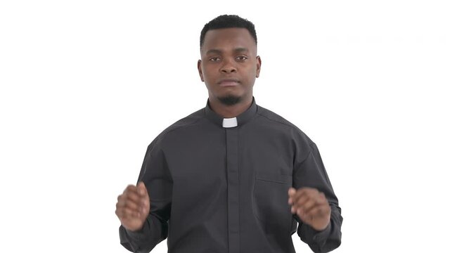 Portrait of doubting African priest showing so-so gesture by waving both hands isolated on white background