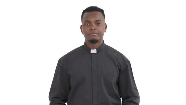Portrait of hesitant African priest showing so-so gesture by gentle rocking left-right movement with left hand isolated on white background
