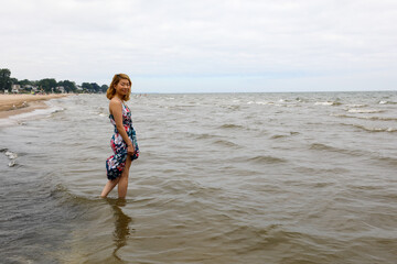 Fototapeta na wymiar Happy young woman walking in the water on the Lake Ontario shoreline