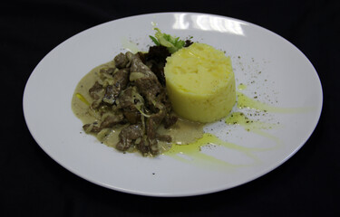 Puree with meat and basil on the white plate. Close-up