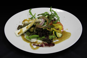 Salad of cucumbers, tomato, arugula, onions, olives and cheese on the plate