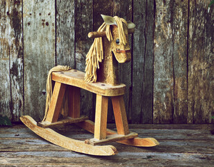 Antique rocking horse on a wooden backdrop.