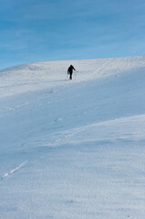 A lone man climbs a snow covered hill in Olympic park,  Munich, Germany.