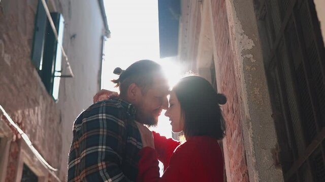 Close shot of young couple kissing and smiling on a bright sunlight. Charming lovers spending their vacation in the most romantic city of Italy. Let the whole world wait. Concept of love and sincerity