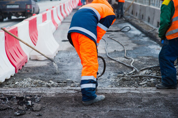 Road worker removes old asphalt with a jackhammer