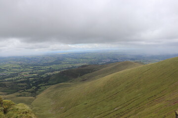 Green rolling hills with grey cloudy sky 