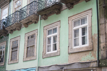 Obraz premium Typical old and vintage portuguese green painted old facade with five windows and balconies in the city center of Porto Portugal 
